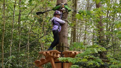 Ein Mädchen klettert in den Bäumen im ROPETECH Seilpark, Dälhölzli Bern